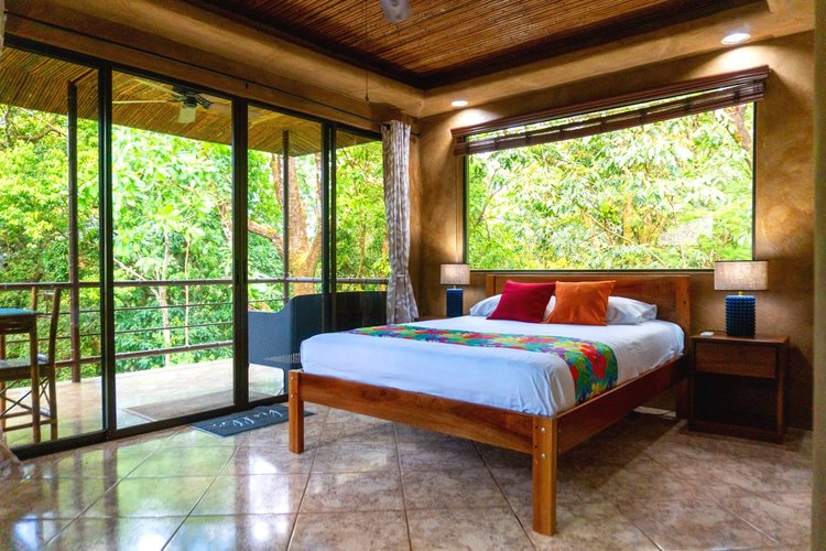 Villa bedroom opening onto a balcony above the rainforest